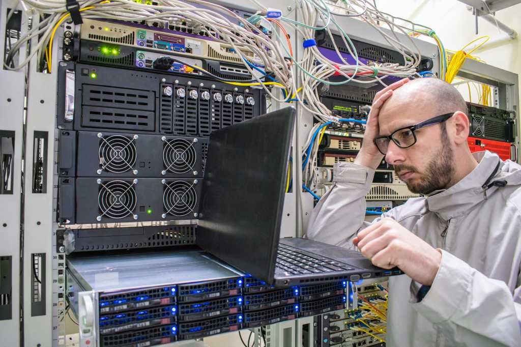 Programmer with glasses made a mistake when working in the server room. The system administrator took his hand to the head in the data center. The concept of failure in the development of software.