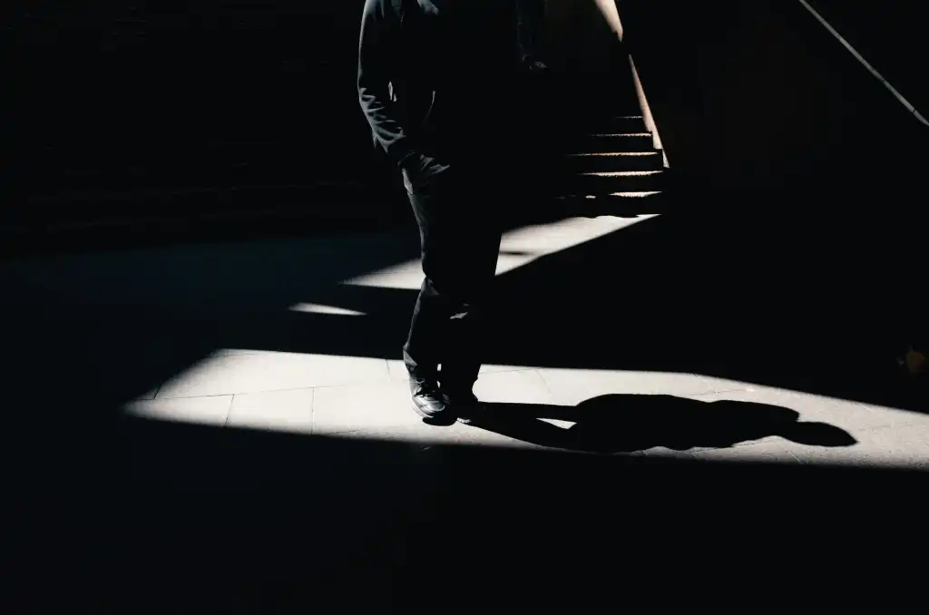 Man walking in shadows at bottom of stairs, visualizing a shadow AI agent