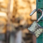 shutterstock 144587243 open padlock hanging on a green gate rusty padlock unlocked padlock