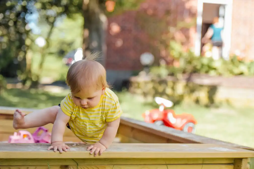 baby trying to get out of his sandbox