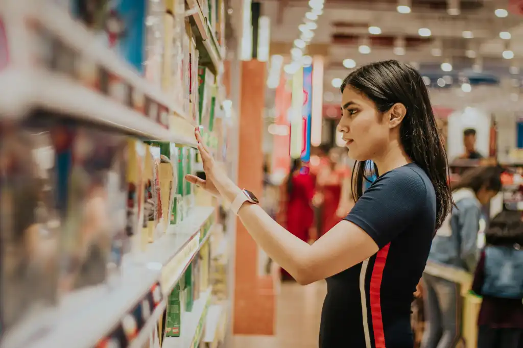 Young woman selecting a product off of a store shelf.