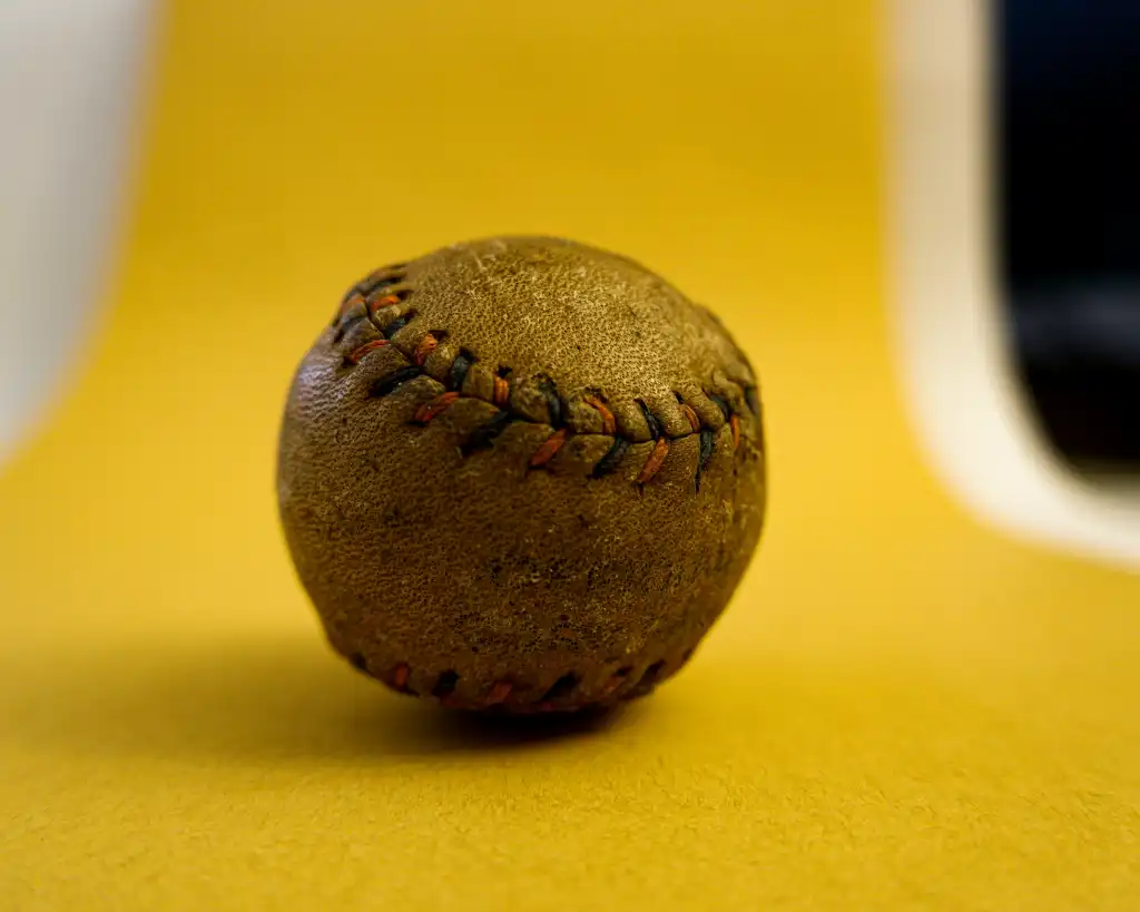 Worn brown baseball on a yellow table.