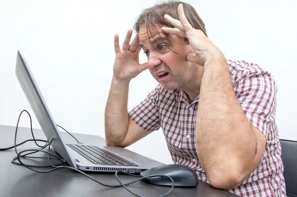 The confused unhappy user is looking at the computer screen. Surprised stressed man looking at laptop. System error on computer.