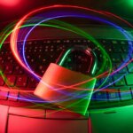 Colored lights over a padlock on top of a laptop computer. Indicates security.