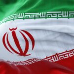 Close-up view of the Iran national flag waving in the wind. The Islamic Republic of Iran is a State of Asia located at the eastern end of the Middle East. Fabric textured background. Selective focus