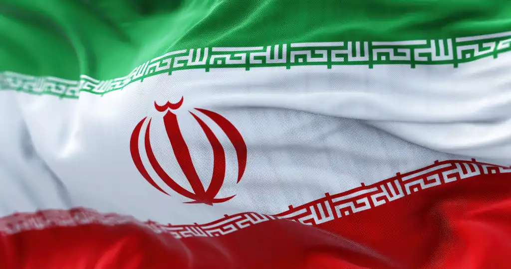 Close-up view of the Iran national flag waving in the wind. The Islamic Republic of Iran is a State of Asia located at the eastern end of the Middle East. Fabric textured background. Selective focus