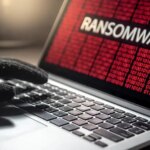 Male hacker hand on laptop computer keyboard with red binary screen of ransomware attacking. Cyber attack and Internet data security concept