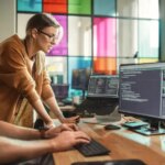 Male Data Scientist and Female Developer Working With Errors in Code on Desktop Computer in Creative Office. Caucasian Man and Woman Succesfully Fixed a Software Bug And High Five Each Other.
