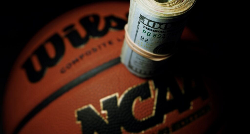 A picture of an NCAA basketball with money on top of it