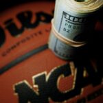 A picture of an NCAA basketball with money on top of it