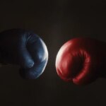blue and red boxing gloves face off against a black background