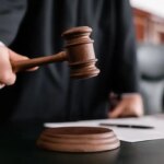partial view of blurred judge holding gavel during sentencing in court