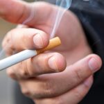 A picture of a hand holding a lit cigarette