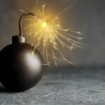 Old fashioned black bomb with lit fuse on grey table, space for text