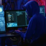 Hackers in dark room running code to breach defenses and exploit weaknesses in computer systems. Evil developers in basement getting past companies security networks, handheld camera shot