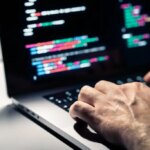 Hacker with malware code in computer screen. Cybersecurity, privacy or cyber attack. Programmer or fraud criminal writing virus software. Online firewall and privacy crime. Web data engineer.