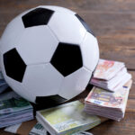 A picture of a soccer ball with money underneath it