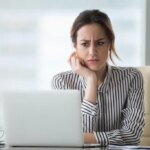 Confused businesswoman annoyed by online problem, spam email or fake internet news looking at laptop, female office worker feeling shocked about stuck computer, bewildered by scam message or virus