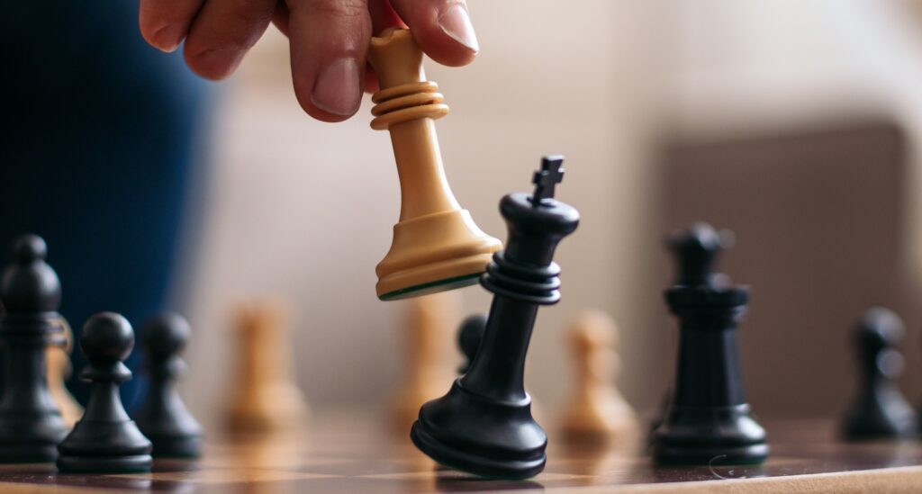 A picture of a person moving a chess piece on a board.