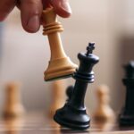 A picture of a person moving a chess piece on a board.