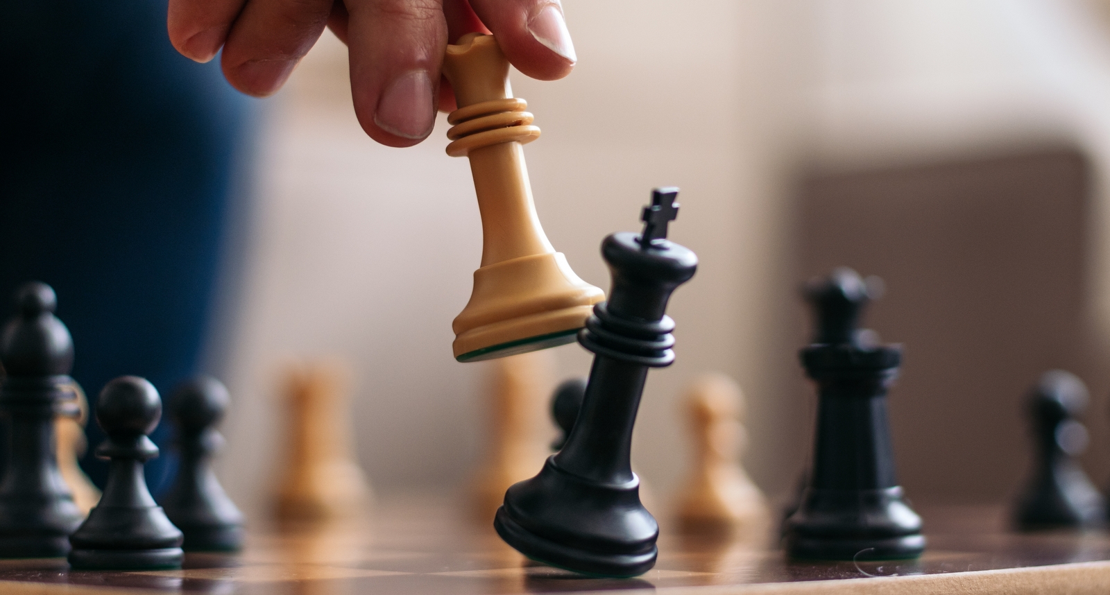 A picture of a person moving a chess piece on a board.