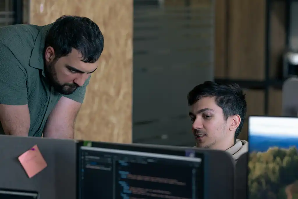 Two men working on computers in an office Code inspection with programmers