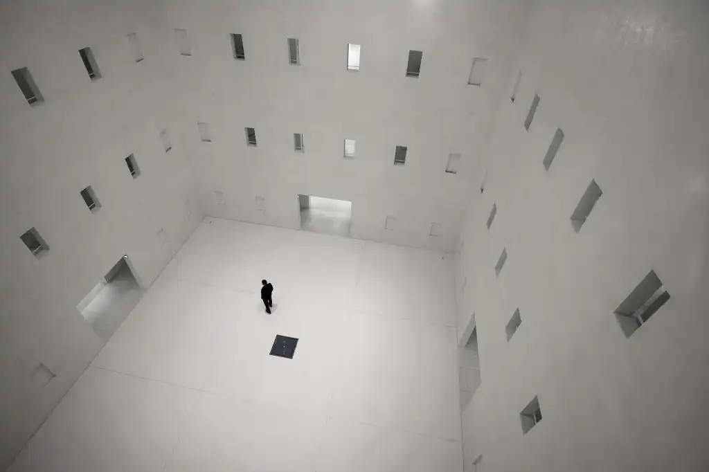 Black and white image of a man in a tiled room with many opoen doors and windows