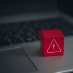 Red-warning-cube-on-a-laptop-keyboard Sicherheitslücke Alarm
