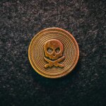 a gold and black emblem of skull on a coin