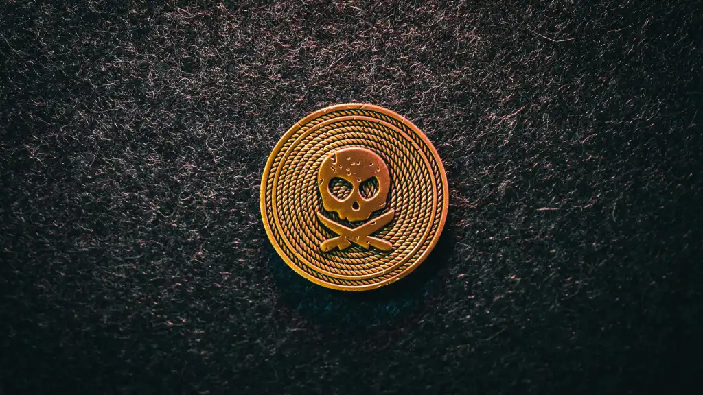 a gold and black emblem of skull on a coin