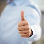 Business man, thumbs up and motivation in office, support and promotion or agreement in like emoji. Male person, yes and employee satisfaction for career opportunity, winner and thank you gesture