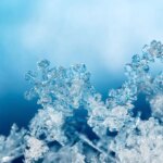 shutterstock 757358335 frozen snowflakes snow ice against clouds and blue sky natural snowflakes on snow