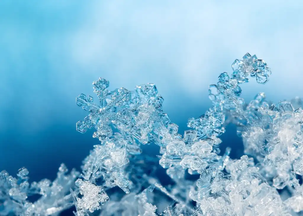 shutterstock 757358335 frozen snowflakes snow ice against clouds and blue sky natural snowflakes on snow