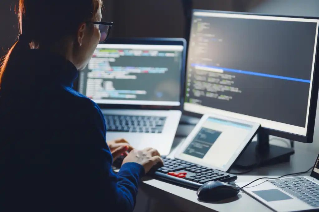 Young Asian woman, developer programmer, software engineer, IT support, wearing glasses working hard at nitght overtime on computer to check coding in bugging system. Back view