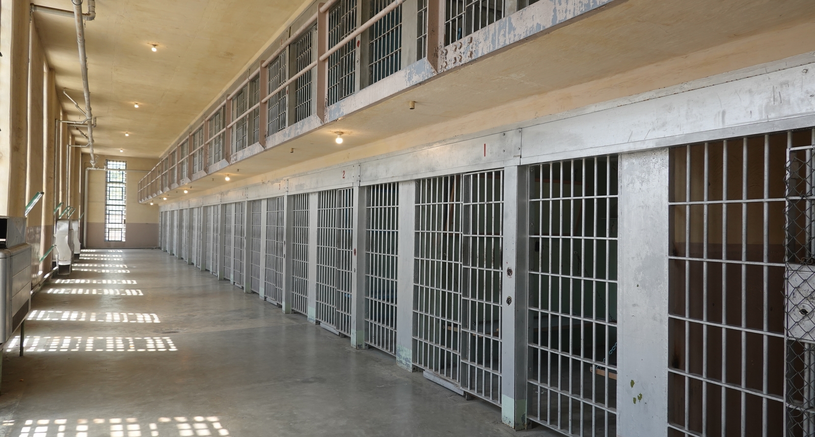A picture of a hallway full of prison cells.