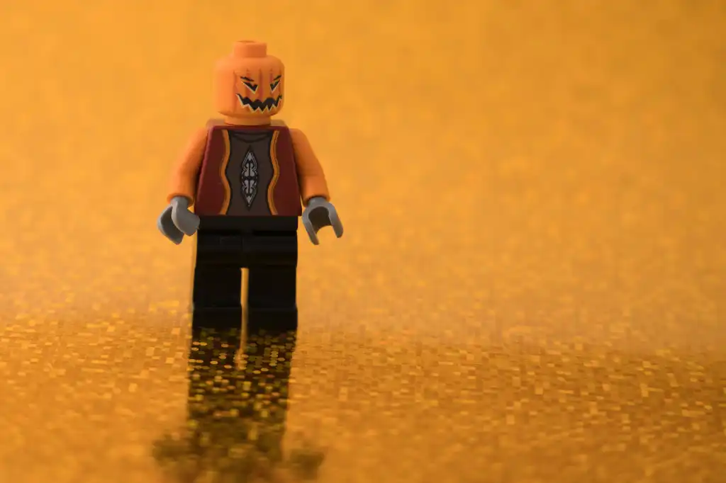 a pumpkin head lego figure is standing on a shiny orange surface