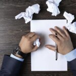 Close-up of male hands with pen over document crumpled paper