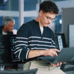 Man, programmer and office with laptop for coding, software development or app design. Male person, coder or developer with computer or technology for cybersecurity, web or IT services at workplace